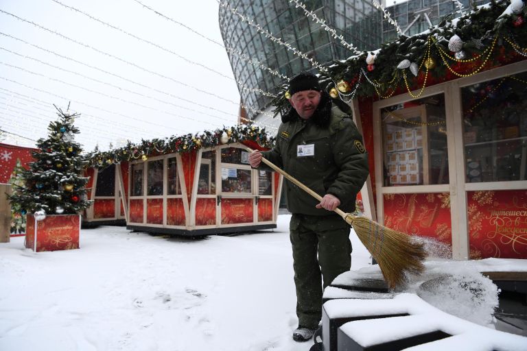 Мужчина убирает снег на площадке фестиваля Путешествие в Рождество в Москве Мужчина убирает снег на площадке фестиваля Путешествие в Рождество в Москве