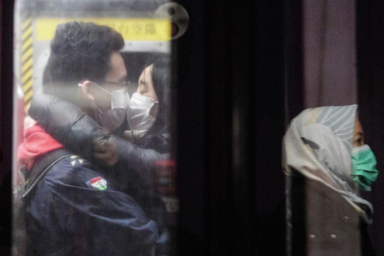 Пара в масках лица в метро Гонконга Пара в масках лица в метро Гонконга