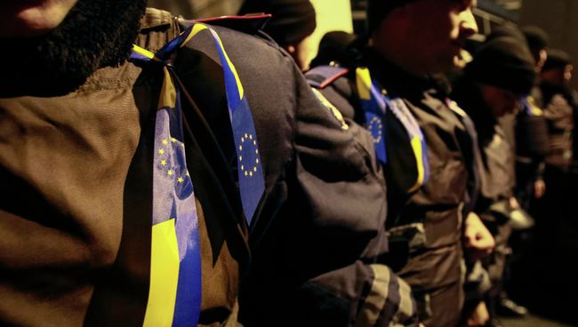 Ленты с украинскими флагами и флагами Евросоюза на полицейских во время митинга в поддержку евроинтеграции, Киев Ленты с украинскими флагами и флагами Евросоюза на полицейских во время митинга в поддержку евроинтеграции, Киев