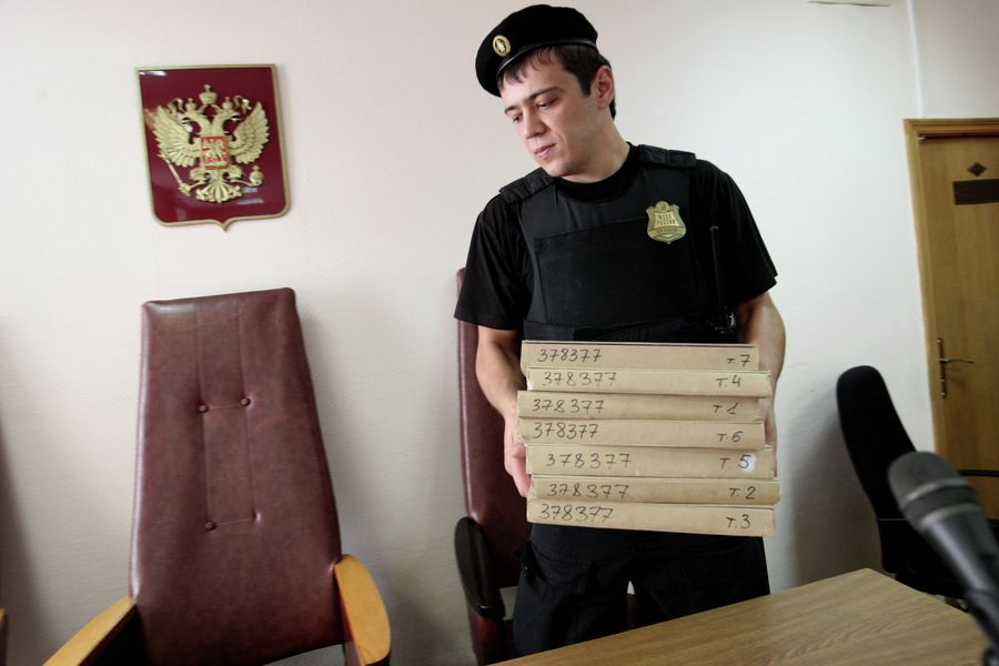 Судебный пристав держит в руках папки с документами
