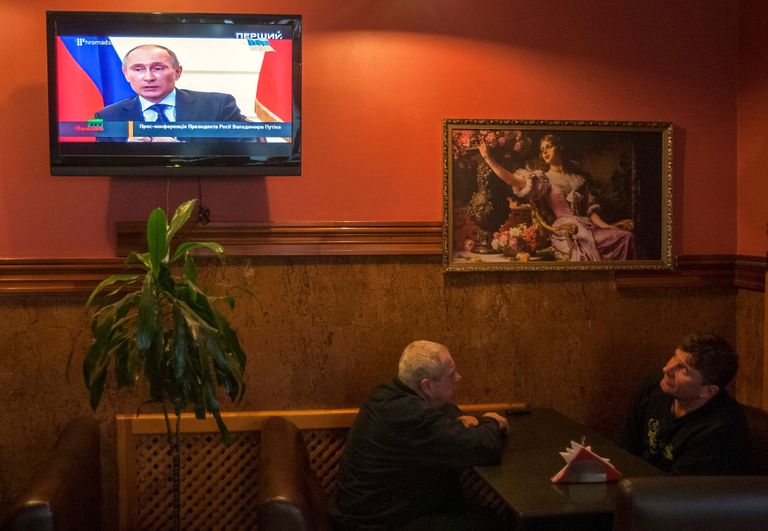 Жители Киева во время просмотра ТВ трансляции пресс-конференции президента России Владимира Путина