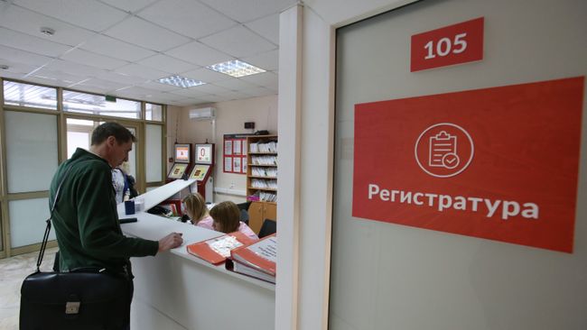 Посетитель у регистрационного стола в поликлинике Посетитель у регистрационного стола в поликлинике