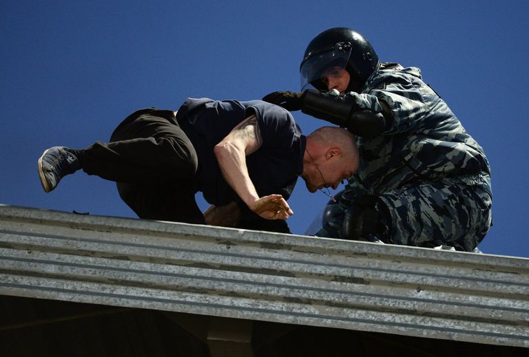 Сотрудник правоохранительных органов (справа) и болельщик на крыше стадиона Сотрудник правоохранительных органов (справа) и болельщик на крыше стадиона